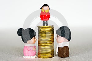 Between mother and father toy figures pile of coins with a child on it, concept of inheritance