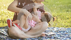 Mother feed breastmilk to her daughter in park