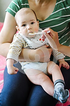 Mother feeding baby, baby infant eating from spoon