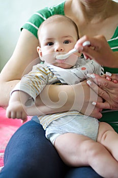 Mother feeding baby, baby infant eating from spoon