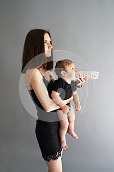 Mother feeding baby from bottle on grey background