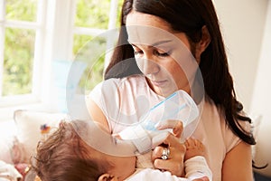 Mother Feeding Baby Boy From Bottle At Home