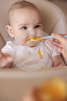 Mother feeding baby boy while introducing solid food