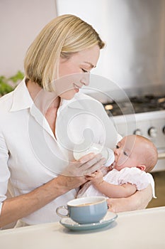 Mother feeding baby with coffee smiling