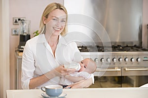 Mother feeding baby with coffee smiling