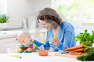 Mother feeding baby first solid food