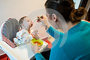 Mother feeding baby first solid food. food diversification