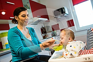 Mother feeding baby first solid food. food diversification