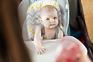 Mother Feeding Baby girl In High Chair