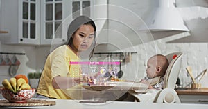 Mother feeding baby in kitchen