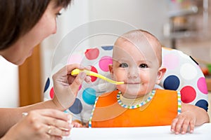 Mother feeding baby on kitchen