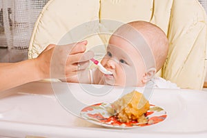 Mother feeding baby with a spoon. baked apple