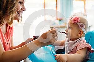 Mother feeding baby with spoon indoors