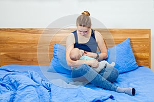 Mother feeding by breasts her baby at home