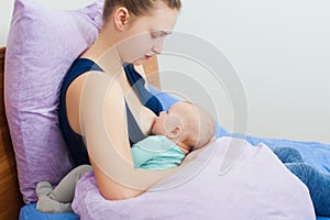 Mother feeding by breasts her baby at home