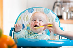 Mother feeding capricious baby with a spoon photo