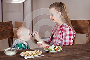 Mother feeding child. First solid food for young kid