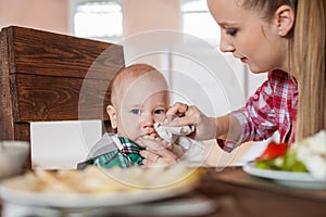 Mother feeding child. First solid food for young kid