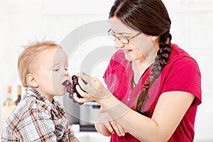 Mother feeding child with grape