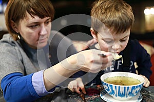 Mother feeding child with soup