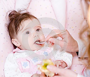 Mother feeding her baby apple puree