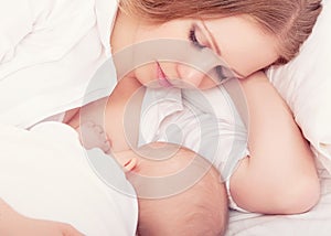 Mother feeding her baby in the bed. sleeping together