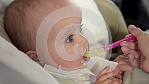 Mother feeding her baby girl with a spoon.