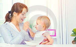 Mother feeding her baby girl with a spoon. Baby food