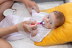 Mother feeding her baby girl with a spoon. Mother giving food to her four-month old baby