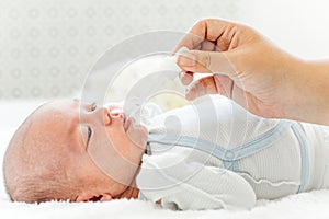 Mother feeding her baby with a milk formula from a bottle