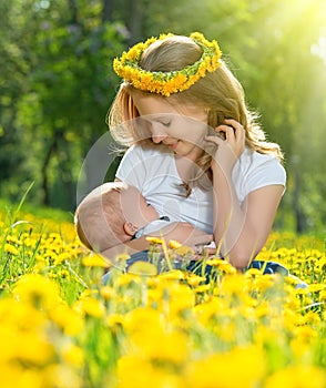 Mother feeding her baby in nature green meadow with yellow flow