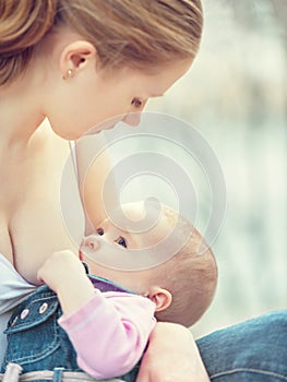 Mother feeding her baby in nature outdoors in the park