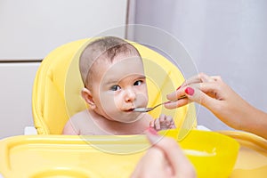 Mother feeding her baby son with fruit puree