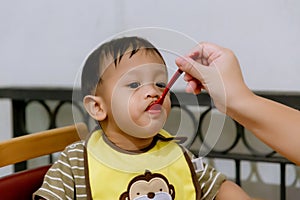 Mother feeding her baby with spoon. Mother giving healthy food to her adorable child at home.