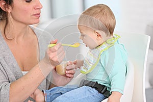 Mother feeding her child with stewed fruits photo