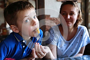 Mother feeding her son with fried rapana