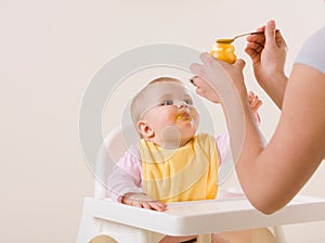 Mother feeding hungry baby in highchair photo