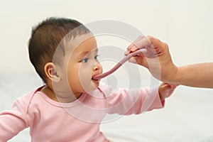 mother feeding liquid medicine to sick infant baby with spoon