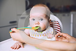 Mother feeding little baby with spoon