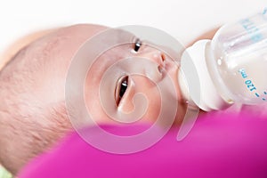 Mother feeding newborn baby boy with milk in nursing bottle