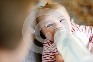 Mother feeding newborn baby daughter with milk in nursing bottle