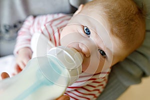 Mother feeding newborn baby daughter with milk in nursing bottle