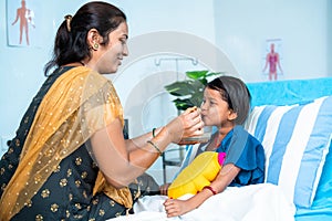 Mother feeding porridge to ill kid while admitted at hospital ward - concept of parental caring, medical treatment and