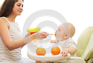 Mother feeds baby spoon on table home
