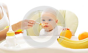 Mother feeds baby spoon on the table home
