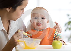 Mom feeds her kid. Baby is crying, capricious and refusing to eat photo