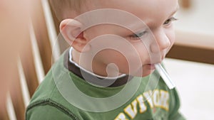 Mother feeds her young son with ice cream from a spoon. They are sitting in a street cafe. The boy really likes the