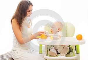 Mother feeds little baby spoon on table home