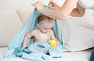 Mother found her baby under blue towel playing with yellow rubber duck