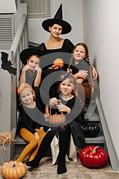 Mother and four girls posing for haloween photo, sitting on the stairs.
